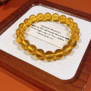 Detail of honey yellow crystal beaded bracelet with transparent round beads on wood