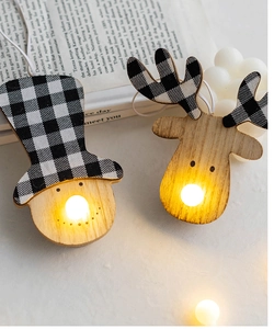 Macro detail of wooden Christmas snowman and elk ornament with warm glowing LED light