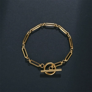 Detail of gold paperclip chain bracelet featuring a polished toggle clasp closure