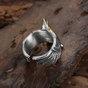 Adjustable silver and gold eagle ring with detailed feather texture on rustic wood