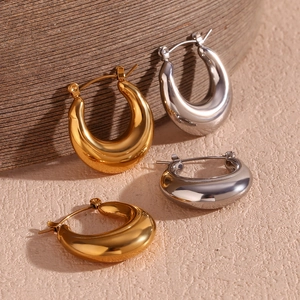 Polished hollow U-shaped earrings in gold and silver finish on textured paper