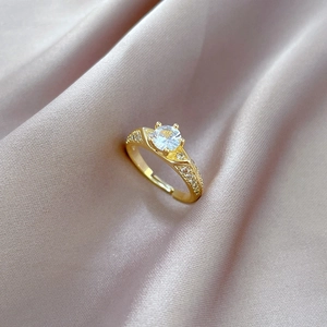 Detailed macro view of a gold four-prong solitaire ring with side accents on silk