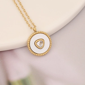 Macro shot of gold necklace with round shell pendant and triangle zircon stone