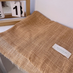 Detail view of cotton linen scarf texture and fringe with white woven brand label