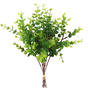 Detail of faux eucalyptus branch with green leaves and berries in a glass vase