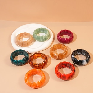 Polished acrylic geometric stretch bracelets in various colors on a white tray