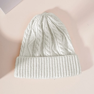 Detail of cream white knit beanie showing classic cable stitch pattern and ribbed cuff