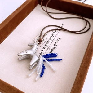 Detail of horse pendant with beaded tail on brown cord in a velvet gift box