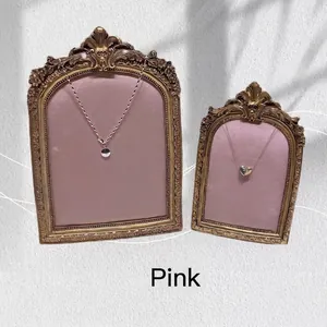 Pink velvet jewelry frames displaying vintage silver and gold pendant necklaces