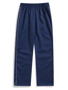 Close-up of navy blue woven joggers featuring white side stripes and elastic waist