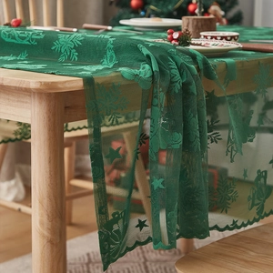 Detail eines grünen Weihnachts-Tischläufers aus Spitze mit Hirsch- und Schneeflockenmuster