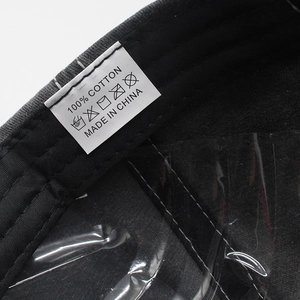 Detail view of the 100% cotton inner lining and wash care label of the black baseball cap
