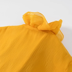 Detailed close-up of yellow pleated fabric and ruffle stand collar on a women's top