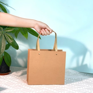 Minimalist brown kraft paper gift bag with reinforced handles shown in a lifestyle setting