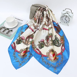 Blue and cream carriage chain print satin silk scarf draped over a leather bag