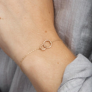Detail of interlocking golden rings on a dainty chain worn by a model for a minimal look