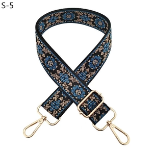 Detail of bohemian wide bag strap with blue floral embroidery and gold metal hooks