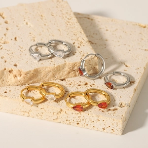 18K gold plated heart zirconia hoop earrings for women on a beige stone display
