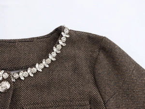 Détail du col d'un manteau à chevrons avec broderie florale étincelante en strass
