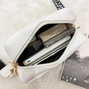 White quilted camera bag with wide printed shoulder strap showing interior storage capacity