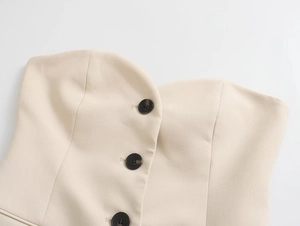 Detail of beige tube top featuring a sweetheart neckline and dark brown contrast buttons
