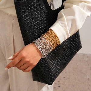Close-up of multilayered gold and silver metal chain bracelets styled on a woman's wrist