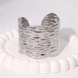 Macro shot of silver wide bangle featuring unique wavy texture and polished metal finish