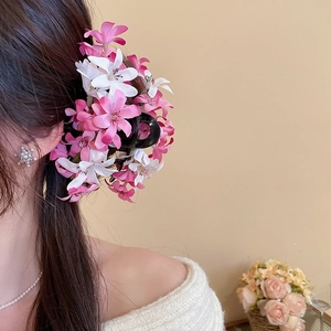 Détail d'une pince à cheveux avec fleurs en tissu rose et blanc sur un modèle