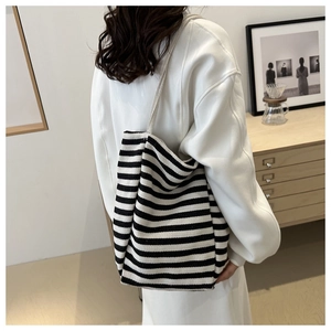 Detail view of large black and white striped canvas bucket bag worn by model in studio