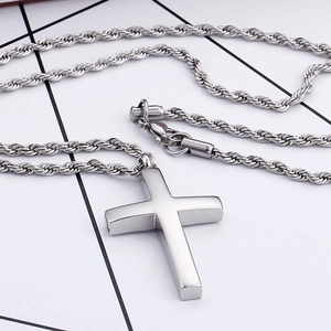 Détail du pendentif croix en acier inoxydable argenté avec chaîne torsadée sur blanc