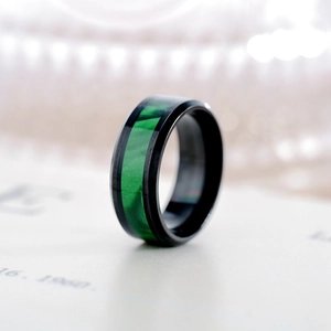 Detailed close-up of a black stainless steel ring with a vivid green marbled inlay.