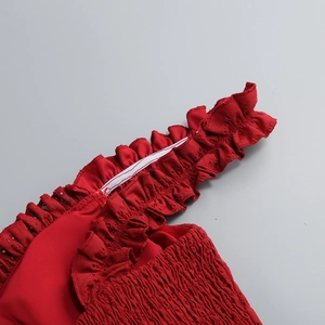 Detailed view of dark red ruffled fabric with elastic band and hollow out textures