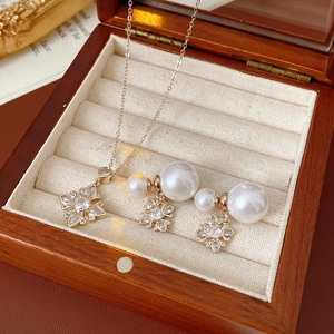 Detailed view of golden snowflake necklace and pearl earrings in a vintage wooden box