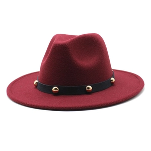 Detail of burgundy wool fedora hat featuring black band with golden rivet studs