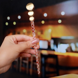 Detail of red and white checkered hair stick with gold circular metal accents