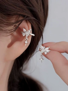 Detail view of silver butterfly ear cuff with zircon star pendant worn on a model's ear