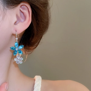 Détail de boucles d'oreilles élégantes à double fleur en zircon bleu et blanc sur un mannequin