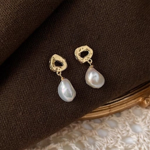 Detail of French baroque pearl earrings with hammered gold metal on a vintage brown fabric