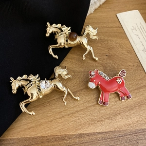 Detailed close-up of horse brooches featuring gold-plated metal and red enamel work