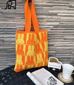 Close-up of bright orange and yellow checkered knit tote with rabbit patterns