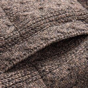 Macro detail of brown cable-knit fabric showing thick texture and side pocket stitching