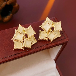 Macro shot of French vintage square enamel earrings with gold frame on leather box