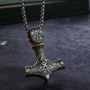 Close-up of Nordic Mjolnir pendant with Celtic patterns in silver and gold finish