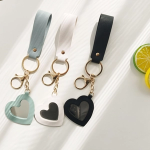 Detail of heart-shaped PU leather mirror keychains in blue, white, and black colors