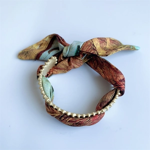 Detail of vintage matte gold beaded chain intertwined with artistic patterned fabric bow