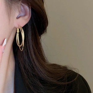Close-up of golden double hoop earrings with textured and polished layered design