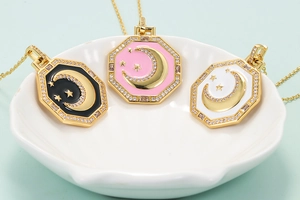 Detail view of octagon star and moon enamel pendants in black, pink, and white colors