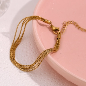 Macro detail of 18K gold-plated multi-layer chain bracelet with adjustable lobster clasp