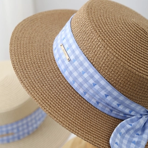 Japanese style woven straw hat with blue plaid ribbon and decorative golden metal tag