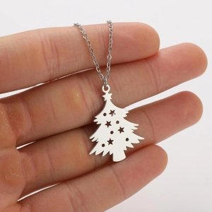 Close-up of hollow Christmas tree pendant necklace with star patterns held in hand